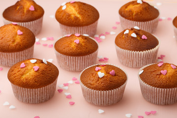 Muffins in paper forms and a lot of small sugar hearts on a mirrored background. Valentine's Day breakfast