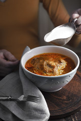 Butter chicken, sauce-boat with cream and a woman at the table