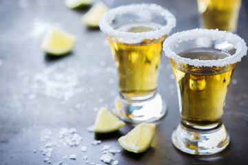 Golden mexican tequila shot with green lime and salt
