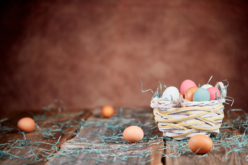 Easter basket and raw eggs on wooden table