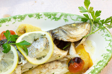 Sea bass baked with potatoes and tomatoes