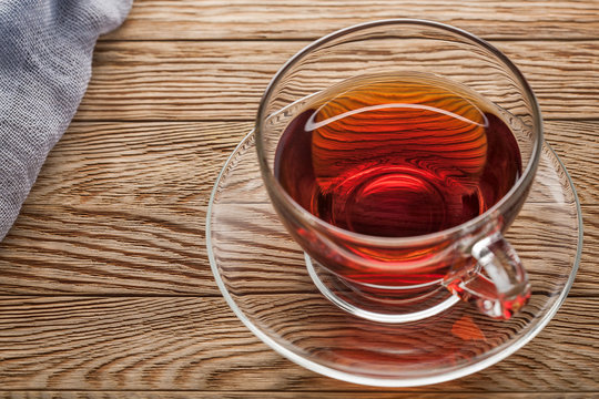 tea in cup of glass on a wooden background with gauze