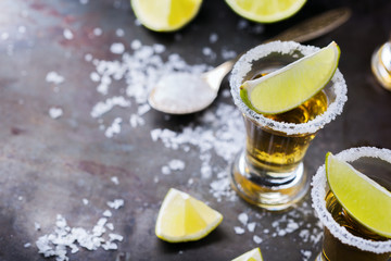 Golden mexican tequila shot with green lime and salt