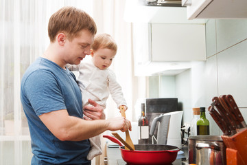the father with the kid cooks food in kitchen