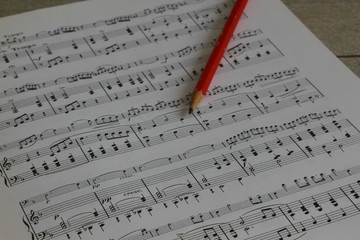 Naklejka premium Musiknoten mit rotem Bleistift auf Holz Hintergrund
