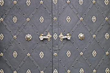Medieval black front door with two handles closeup.