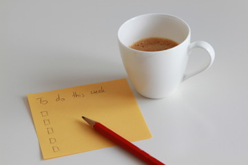 Yellow note paper with to do list and red pencil and coffee