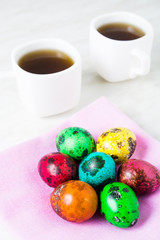 Obraz na płótnie Canvas Easter breakfast with color quail eggs two cup of tea