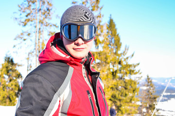 Skier in winter forest, mountains scene, portrait of young man in sunglass mask, ski resort concept