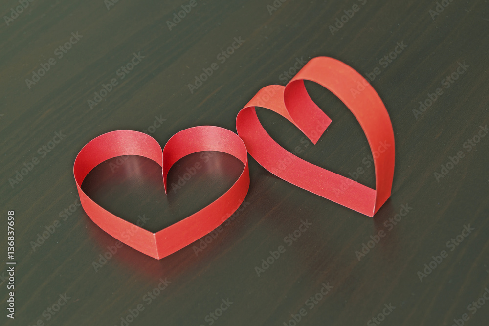 Wall mural two red hearts made of paper strips on a black wooden background