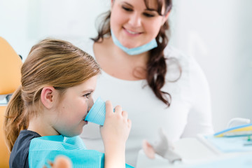 Kind in Praxis von Zahnarzt spült mit Wasser