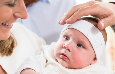 Mutter und Baby bei der Taufe während der Pfarrer seine Hand über Babys Kopf hält und es segnet