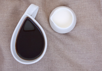 Cup of coffee on linen tablecloths with creamer and empty place
