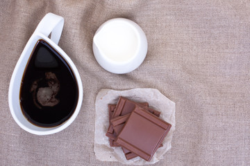 Cup coffee on linen tablecloths with pieces of chocolate, creame