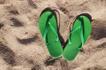 green flip flops in the sand near the sea