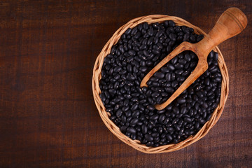 Black beans in scoop on wooden background