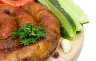 Homemade Sausage on a cutting board with fresh cucumbers, tomato