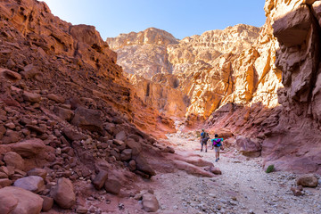 couple people hiking walking stone desert trail backpacking travel - obrazy, fototapety, plakaty