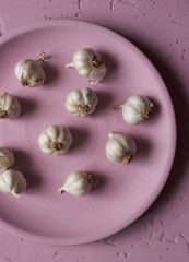 Fototapeta na wymiar Healthy small garlic in pink plate top view