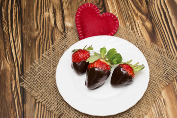 Fresh strawberries dipped in dark chocolate and heart on wooden background. Valentine's Day