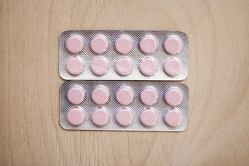Pill pharmacy medicine health care template concept. Pink drug on isolated wooden board background. Medicament blister pack with pills