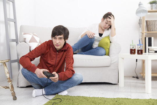 Girl is bored and angry while her boyfriend playing video game