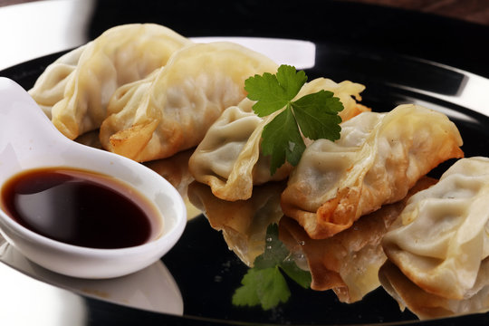 A plate of Japanese gyoza dumplings sitting on a rustic wooden t