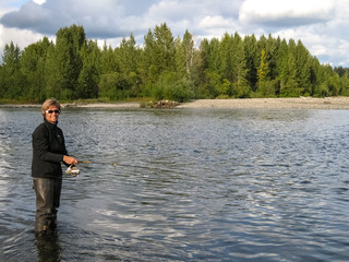 Fototapeta na wymiar Woman fishing for salmon, Talkeetna River, Alaska