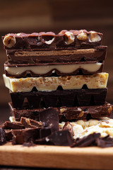 Chocolate bars on a wooden background with chocolate tower