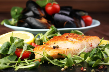 baked salmon grilled pepper lemon on a plate with lettuce leaves