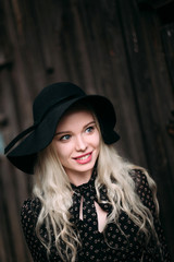 Obraz na płótnie Canvas Beautiful attractive and stylish girl wearing black hat standing posing in city. Nude makeup, best daily hairstyle and great fashion glamour country style. Retouched photo
