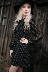 Beautiful attractive and stylish girl wearing black hat standing posing in city. Nude makeup, best daily hairstyle and great fashion glamour country style. Retouched photo
