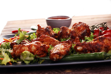 barbecue chicken wings close up on wooden tray with red spice sa