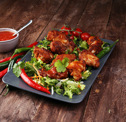 barbecue chicken wings close up on wooden tray with red spice sa