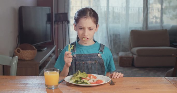Young girl eating a lattuce unhappily 