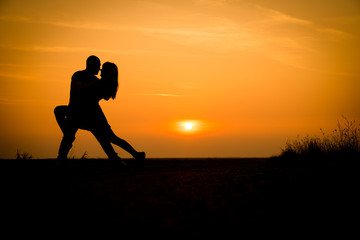 silhouette teenager lovers couple with sun between on sunset dusk sky background: black shadow hand drawn of people hug and kiss people:passion in love concept:decoration,design,valentines