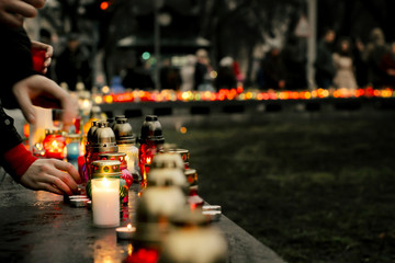 crowd of people lighting candles in city center, mourning victim