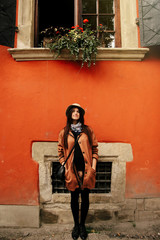 Young beautiful woman hipster standing at  red wall and window i