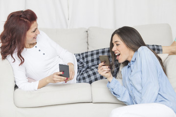 Two happy young female friends having fun together using smartphone