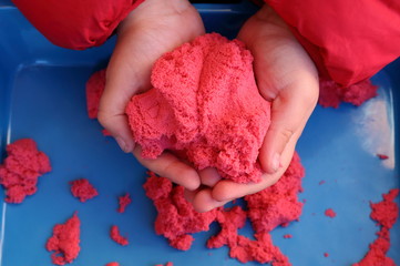 hands of a kid playing with magic sand