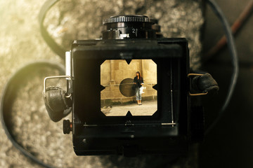stylish happy woman in viewfinder of  analog film camera on back