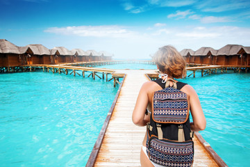 Fototapeta premium Woman with backpack walk on pier at tropical island resort
