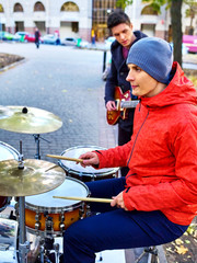 Festival music band. Friends playing on percussion instruments in city park. City and trees in the background. Cold weather outdoor.