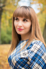 beautiful, dreamy girl with long straight hair in a blue long dress in the park in autumn