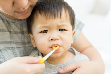 Asian baby uses toothbrush