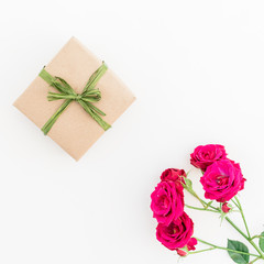 Craft gift box and red roses isolated on white background. Flat lay, top view. Floral background.