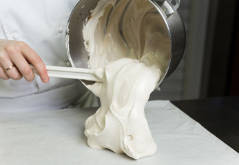 A beautiful rich and creamy , white whipped meringue mixture in a large metal mixing bowl, being...