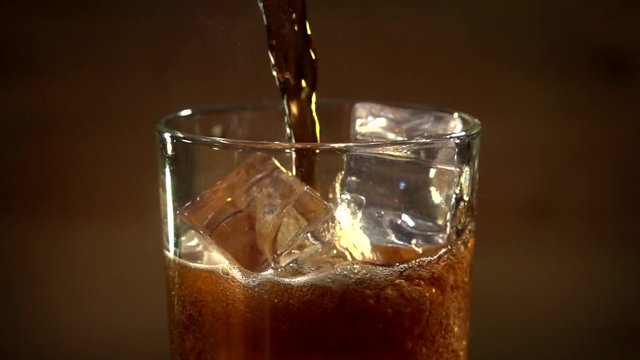 Cola poured into glass with ice. Cola and ice in glass. Bubble float. Slow motion 240 fps.Slowmo. 