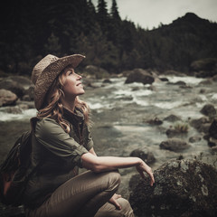 Beautiful woman hiker near wild mountain river.