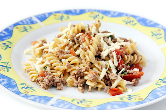 garnished and served pasta with minced meat, tomatoes and mozarella on the plate, copy space